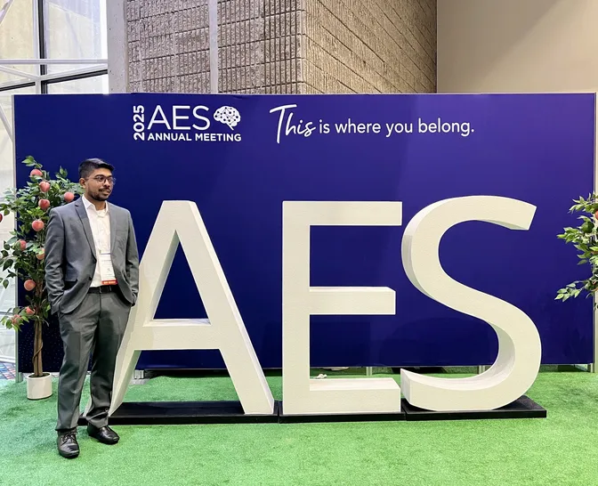 Himanshu Kumar in front of the AES 2025 Annual Meeting sign