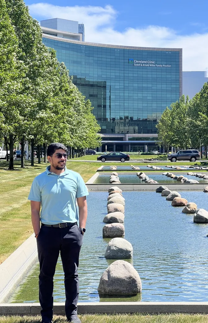 Himanshu Kumar on the Cleveland Clinic main campus, with the reflecting pool and a clinic building behind him